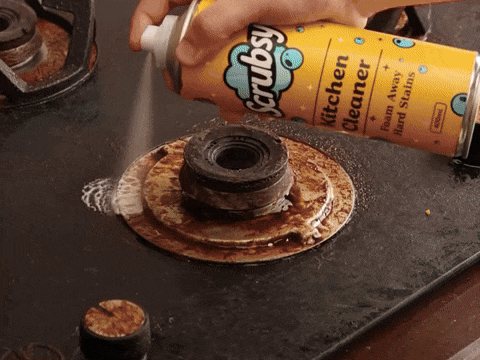 Greasy gas stove burner being sprayed with Scrubsy Kitchen Cleaner