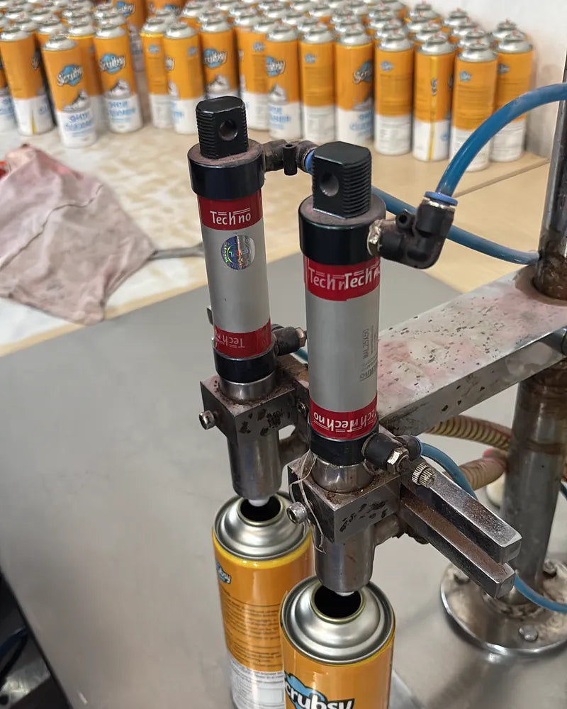 Scrubsy Footwear Cleaner cans being filled on the filling line, with finished cans lined up behind